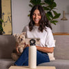 Woman with dog using phone on sofa